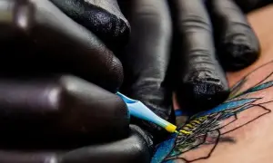 Manos enguantadas crean arte en piel, un detalle de los mejores tatuadores de España.