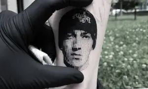 Un rostro en microrealismo tattoo, con líneas finas y detalles precisos, se revela en la piel.