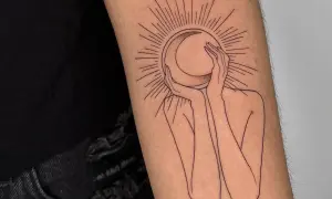 Un tatuaje de una figura abstracta abraza una luna creciente, rodeada por rayos solares. Un diseño minimalista que evoca misterio y conexión cósmica.