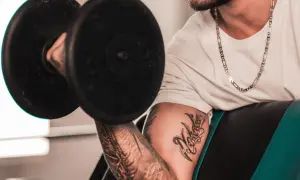 Hombre con tatuaje levanta pesa, mostrando su dedicación al deporte y su arte corporal.