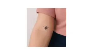 Un delicado tatuaje abeja minimalista adorna el brazo de una persona, un pequeño símbolo de trabajo y dulzura.