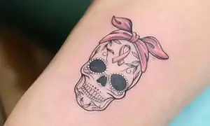 Calavera adornada con lazo rosa y cinta de concienciación, símbolo de tatuajes de superación cáncer.