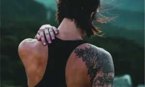 Detalle de un tatuaje cover en la espalda, con flores y elementos gráficos.