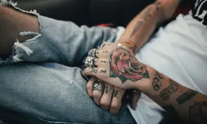 Manos entrelazadas con tatuajes de rosa y números. Reflexionando sobre a qué edad me puedo tatuar en España.