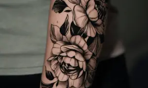 Un primer tatuaje de peonías en blanco y negro, detallado y artístico, adornando un brazo.