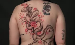 Dragón oriental entre flores de cerezo, un diseño de tatuajes ornamentales que evoca fuerza y belleza.