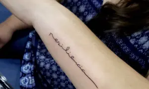 Tatuaje de "resiliencia" en el brazo, un símbolo de la fuerza de la mujer.