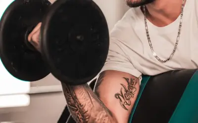 Hombre con tatuaje levanta pesa, mostrando su dedicación al deporte y su arte corporal.