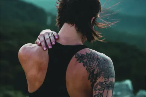 Detalle de un tatuaje cover en la espalda, con flores y elementos gráficos.