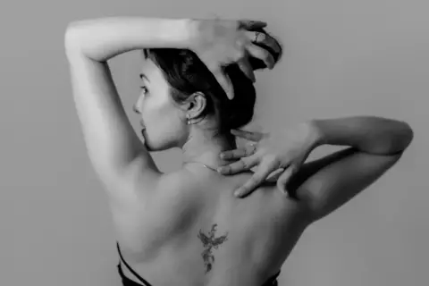 Mujer con un tatuaje de fénix en la espalda, símbolo de renacimiento y fuerza.