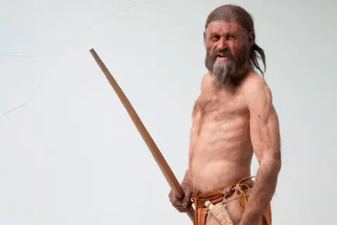 Recreación de Ötzi, el hombre del hielo, mostrando sus antiguos tatuajes y su bastón.