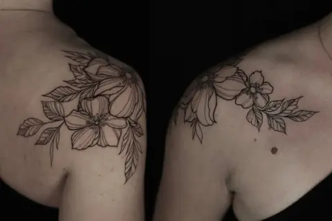 Delicados blackwork tattoos de flores y hojas adornan los hombros, creando un diseño botánico elegante y atemporal.