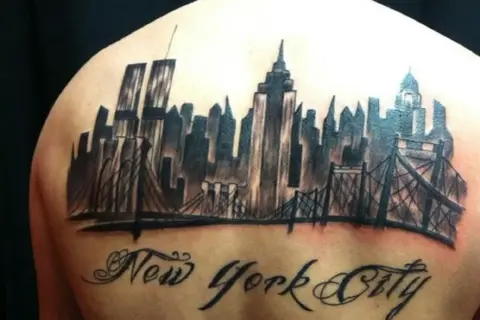 Tatuaje de un horizonte de Nueva York con puentes y el texto "New York City" en caligrafía.