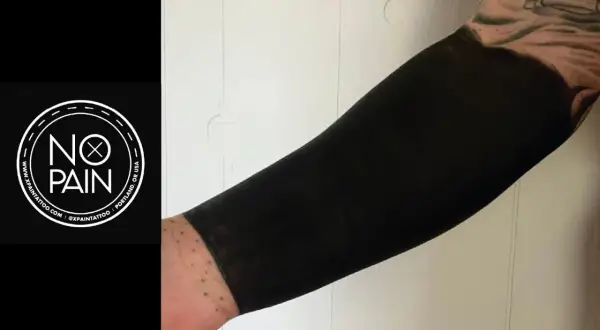 Brazo cubierto con un tatuaje de blackout, un estilo que transforma la piel en una superficie negra intensa.