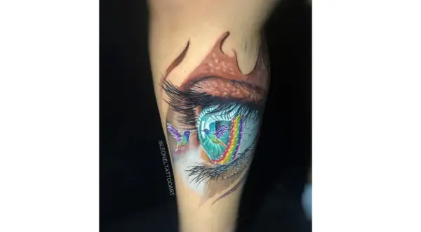Tatuajes ojo con colibríes y arcoíris vibrantes. Un ojo realista con detalles de fantasía, como si los colibríes volaran a través de un portal de colores.