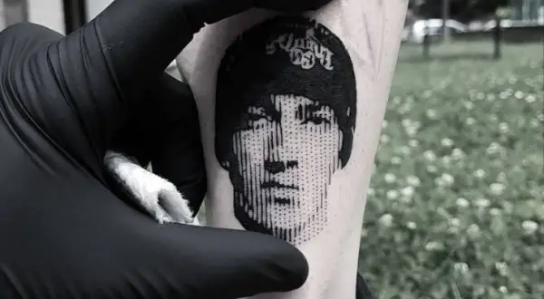 Un rostro en microrealismo tattoo, con líneas finas y detalles precisos, se revela en la piel.