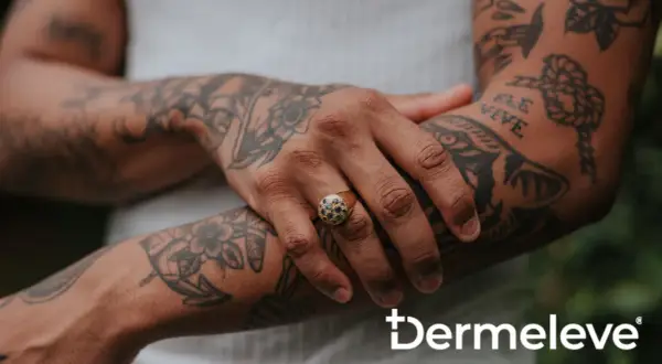 Brazo con tatuajes y un anillo con piedras oscuras. La piel luce sana, sin rastro de costra de tatuaje.