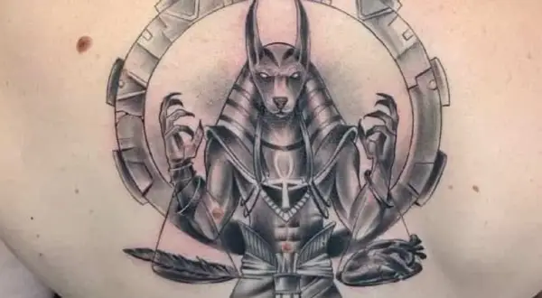Tatuaje de Anubis con un corazón y pluma, simbolizando el juicio y el significado de la vida.