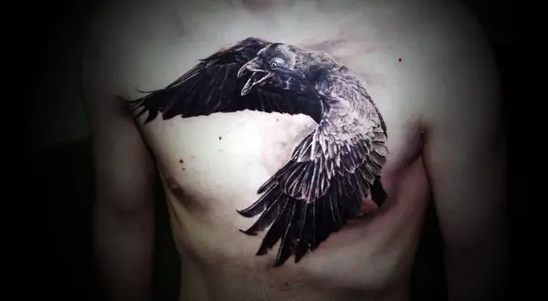 Impresionante tatuaje de cuervos en el pecho, con un ave en pleno vuelo, alas extendidas y pico abierto.