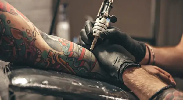 Un artista de **london tattoo** trabaja en un brazo con un diseño colorido.
