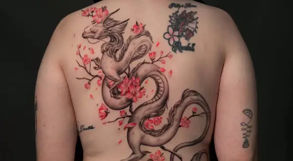 Dragón oriental entre flores de cerezo, un diseño de tatuajes ornamentales que evoca fuerza y belleza.
