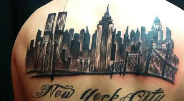 Tatuaje de un horizonte de Nueva York con puentes y el texto "New York City" en caligrafía.