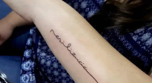 Tatuaje de "resiliencia" en el brazo, un símbolo de la fuerza de la mujer.