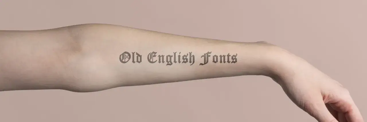 Brazo con tatuajes de letras góticas, "Old English Fonts", que parecen obras de arte permanentes.