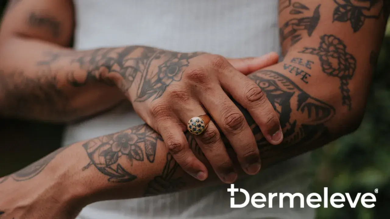 Brazo con tatuajes y un anillo con piedras oscuras. La piel luce sana, sin rastro de costra de tatuaje.