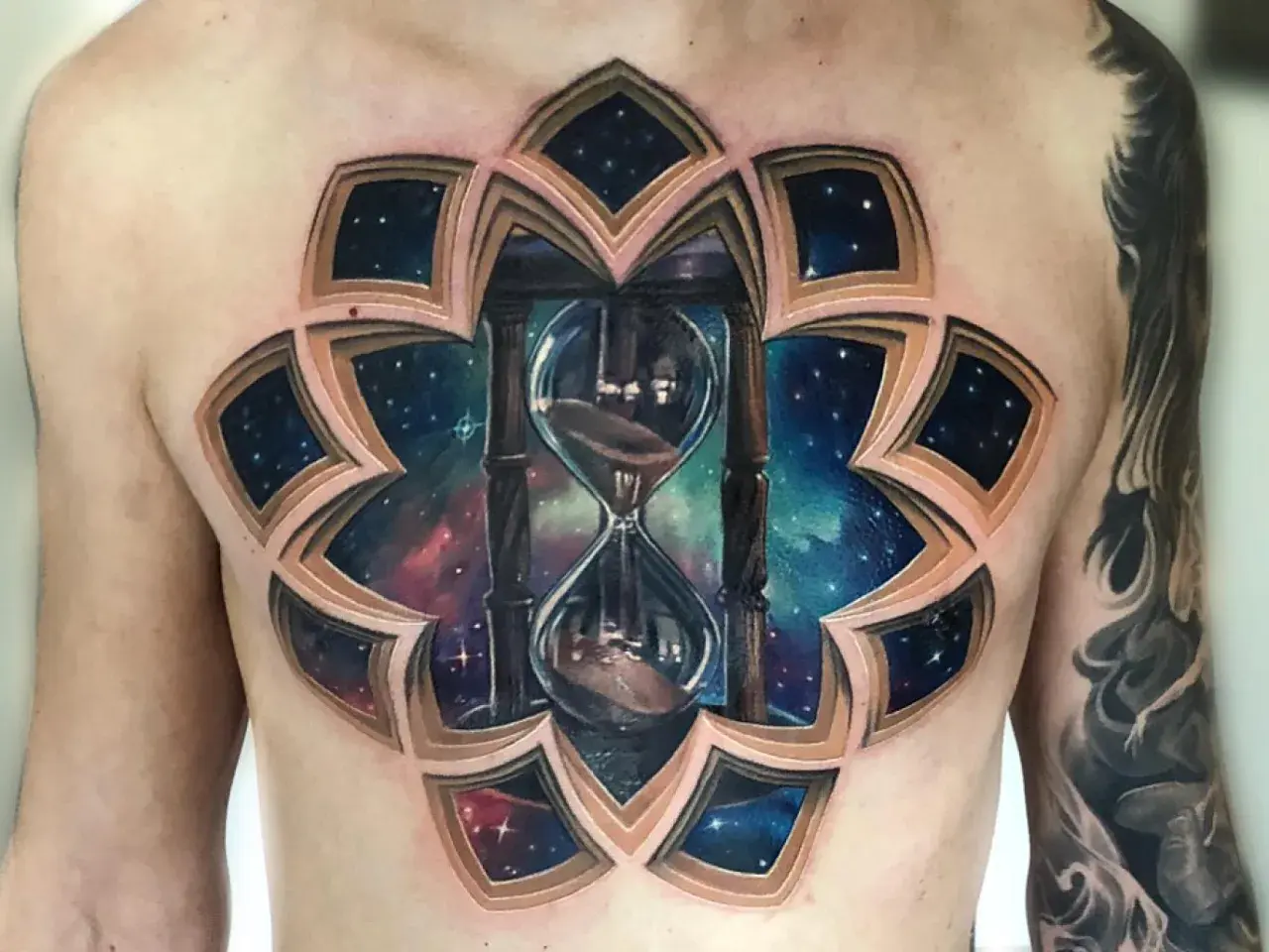 Un impresionante tatuaje 3D en el pecho de un reloj de arena cósmico, con capas que revelan un universo estrellado.