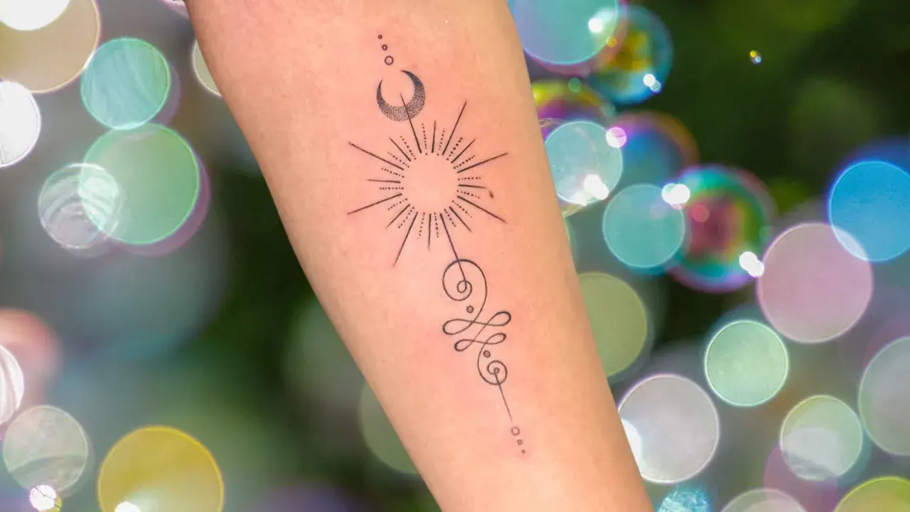 Brazo con tatuaje de sol, luna y símbolo unamalo, representando protección y tatuajes espirituales.