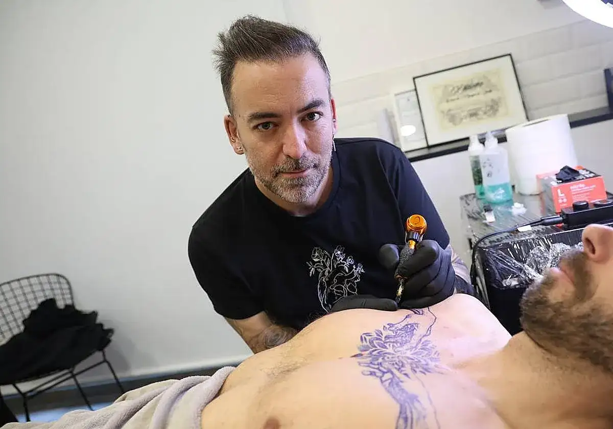 Un tatuador, uno de los mejores tatuadores de España, trabaja en un diseño de mandala en el pecho de un cliente.