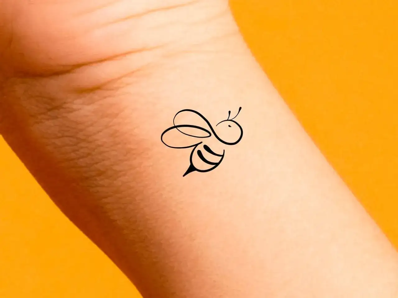 Un delicado tatuaje abeja minimalista, con trazos finos y elegantes, adorna la piel.