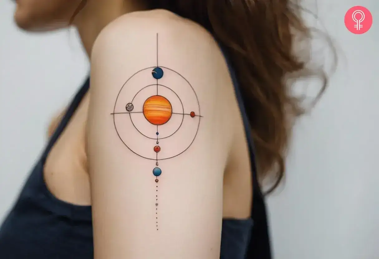 Tatuajes del sistema solar en el hombro de una mujer, con el sol y planetas en órbitas concéntricas.