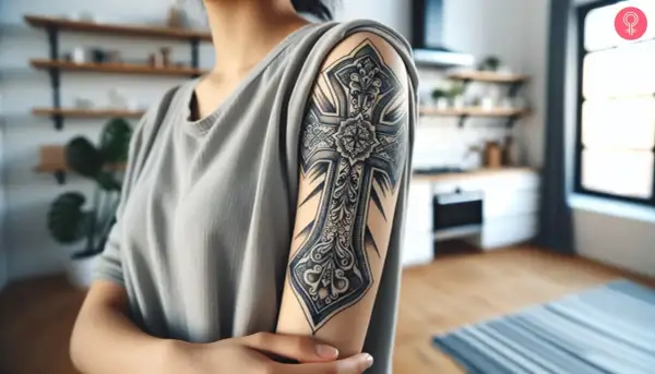Tatuaje de cruz chicana detallado en el brazo de una persona.