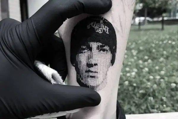 Un rostro en microrealismo tattoo, con líneas finas y detalles precisos, se revela en la piel.