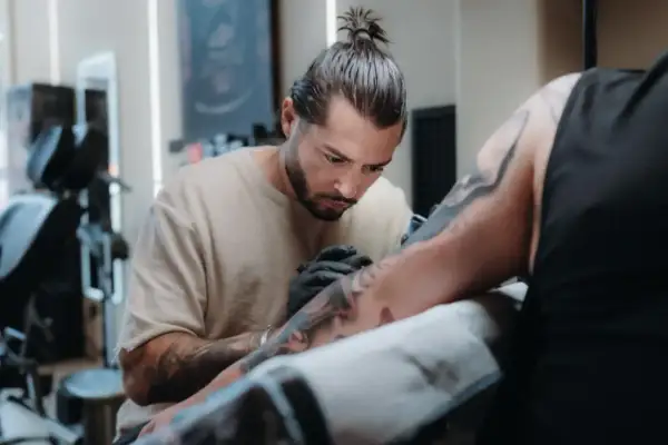 Toni Nova, un artista del tatuaje, trabaja con concentración en el brazo de un cliente.
