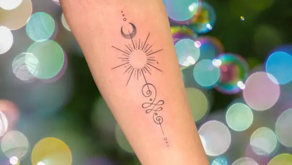Brazo con tatuaje de sol, luna y símbolo unamalo, representando protección y tatuajes espirituales.