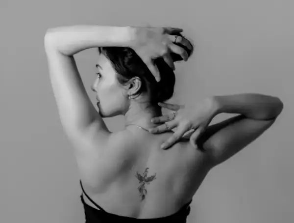 Mujer con un tatuaje de fénix en la espalda, símbolo de renacimiento y fuerza.