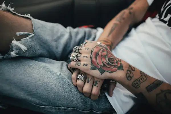 Manos entrelazadas con tatuajes de rosa y números. Reflexionando sobre a qué edad me puedo tatuar en España.