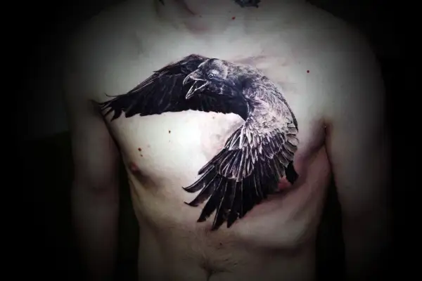 Impresionante tatuaje de cuervos en el pecho, con un ave en pleno vuelo, alas extendidas y pico abierto.