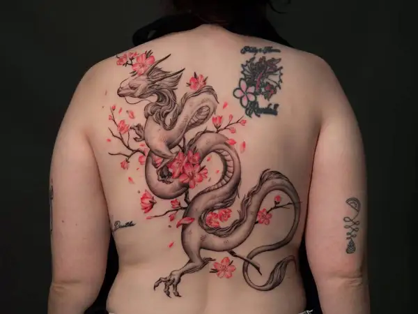 Dragón oriental entre flores de cerezo, un diseño de tatuajes ornamentales que evoca fuerza y belleza.