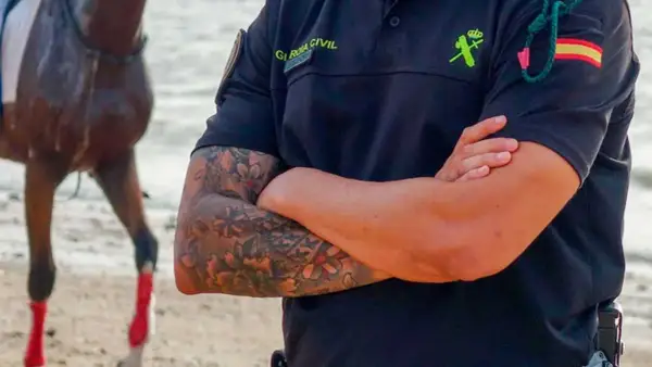 Agente de la Guardia Civil con tatuajes florales en el brazo, mostrando que los tatuajes en el trabajo son cada vez más aceptados.